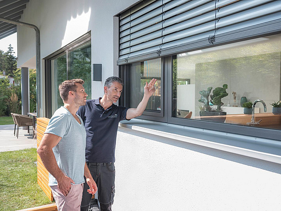 Ein Mann schaut sich mit einem Lämmermann Profi ein Fliegengitter am Fenster an.